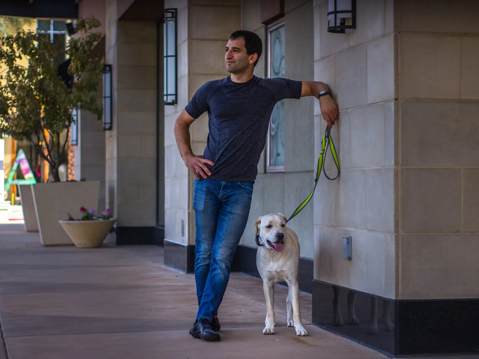 A dog standing at Yoni's side outside a storefront.
