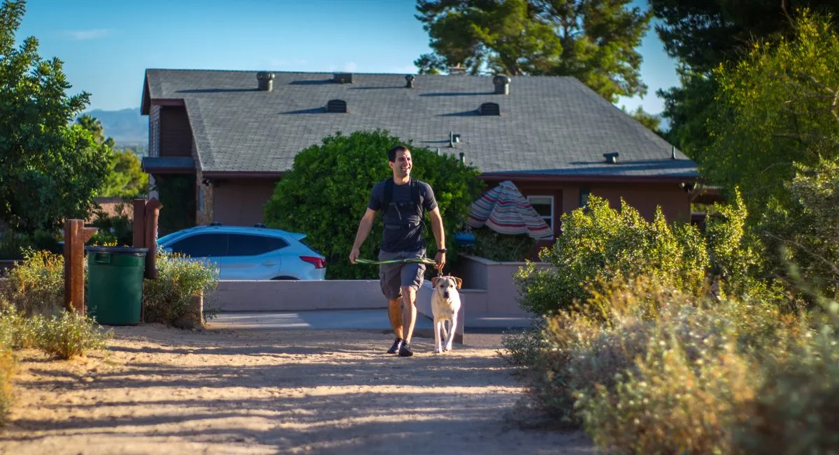 Yoni walking a relaxed dog on a loose leash in a Phoenix neighborhood.